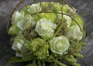 Een compact gestoken afscheidsbloemstukje met grootbloemige wit groene rozen