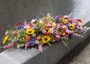 Kistbedekking van een mooie hoeveelheid gemengde bloemen waaronder zonnebloemen