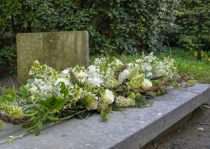 Een persoonlijk afscheid kistbloemstuk in wit groen met materialen ui de eigen tuin.